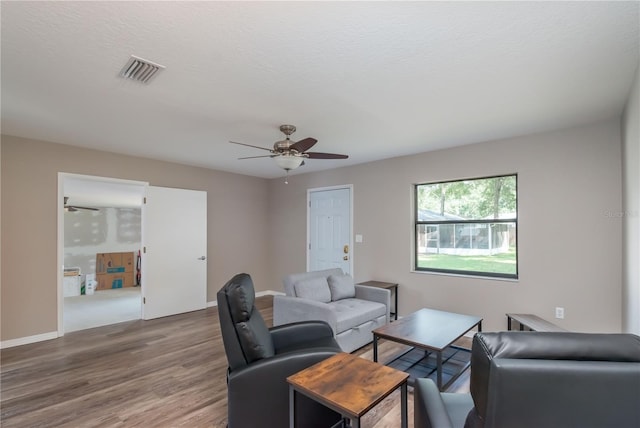 living room with ceiling fan, a textured ceiling, and wood-type flooring