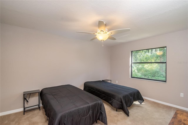 bedroom featuring a textured ceiling, ceiling fan, and light colored carpet