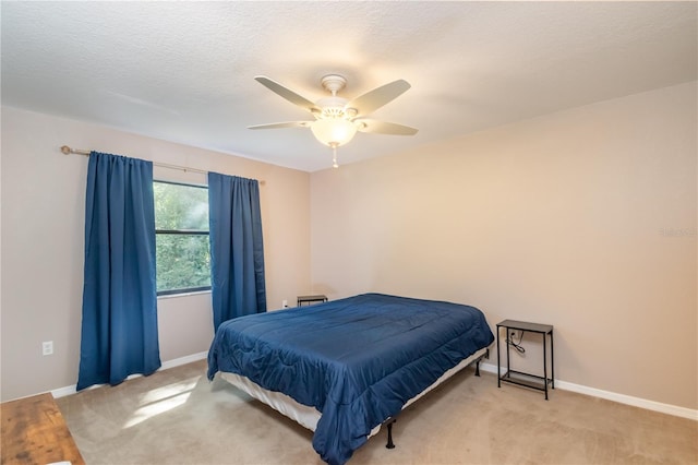 bedroom featuring ceiling fan, light colored carpet, and a textured ceiling