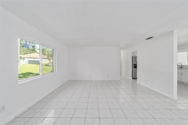 unfurnished room featuring light tile patterned flooring and sink