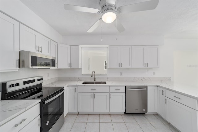 kitchen with light tile patterned floors, white cabinets, stainless steel appliances, and sink