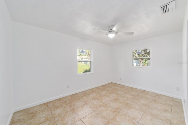 empty room with ceiling fan, plenty of natural light, and a textured ceiling