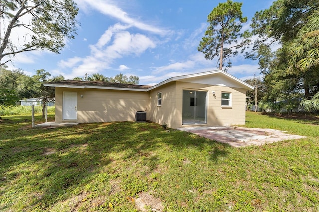 rear view of house with central AC unit, a lawn, and a patio area