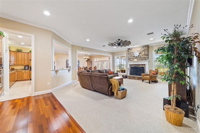 living room featuring ceiling fan with notable chandelier, light hardwood / wood-style floors, crown molding, and a fireplace