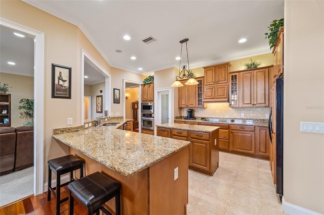 kitchen featuring a kitchen breakfast bar, kitchen peninsula, ornamental molding, pendant lighting, and light tile patterned floors