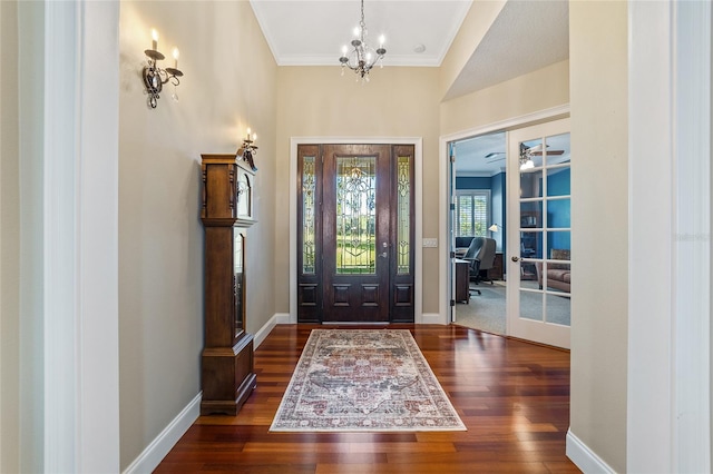 foyer featuring ornamental molding, dark wood-type flooring, and ceiling fan with notable chandelier