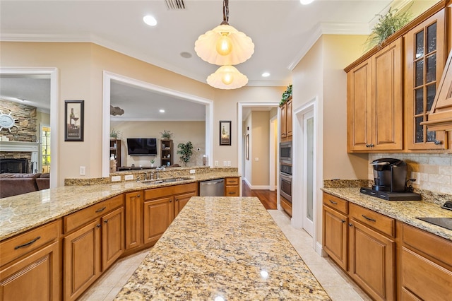 kitchen with ornamental molding, stainless steel appliances, a fireplace, decorative light fixtures, and light stone counters