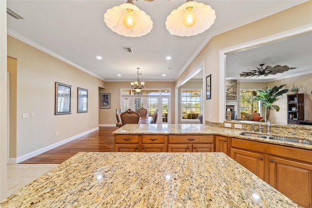 kitchen featuring light hardwood / wood-style flooring, ornamental molding, and light stone counters