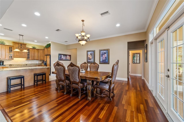 dining space with crown molding, french doors, a chandelier, and dark wood-type flooring