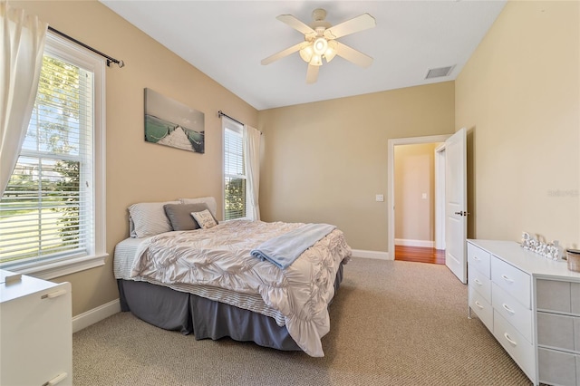 carpeted bedroom with multiple windows and ceiling fan