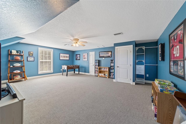 playroom with ceiling fan, a textured ceiling, and carpet floors