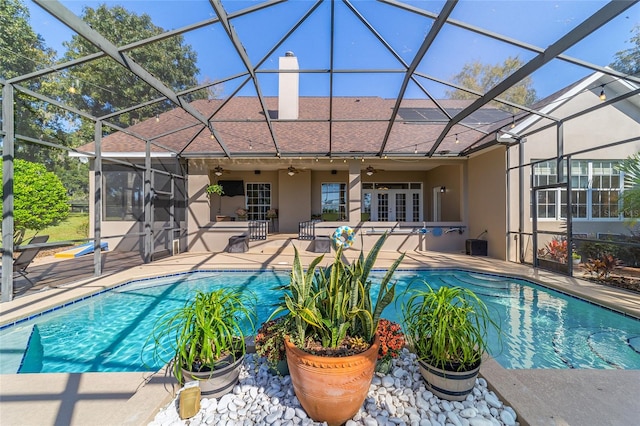 view of swimming pool featuring a patio area, glass enclosure, and ceiling fan