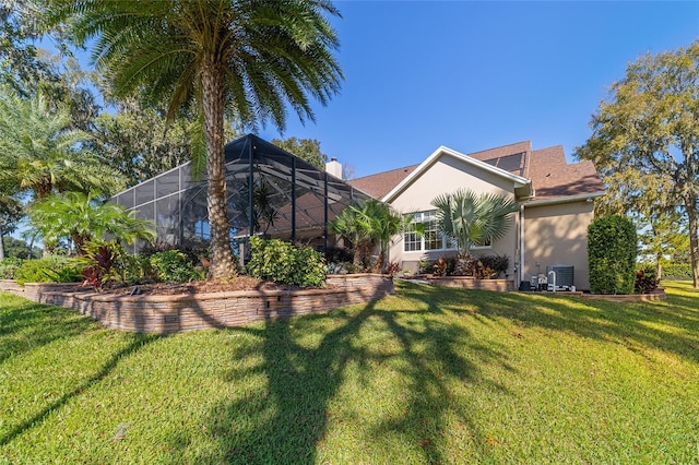 rear view of property with a yard, central AC unit, and a lanai