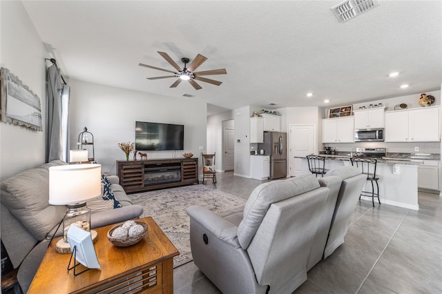 living room featuring ceiling fan and a textured ceiling