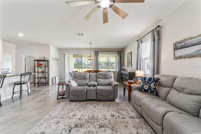 living room featuring ceiling fan, light tile patterned floors, and a textured ceiling