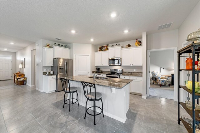 kitchen featuring a kitchen island with sink, sink, stainless steel appliances, and white cabinets