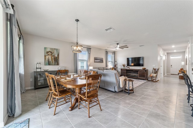 tiled dining space featuring ceiling fan with notable chandelier