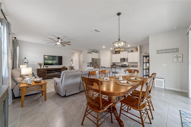 dining space featuring ceiling fan with notable chandelier and light tile patterned flooring