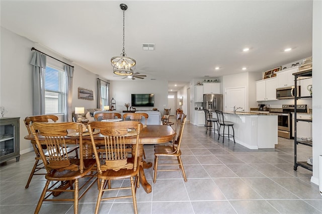 dining space with ceiling fan with notable chandelier, light tile patterned floors, and sink