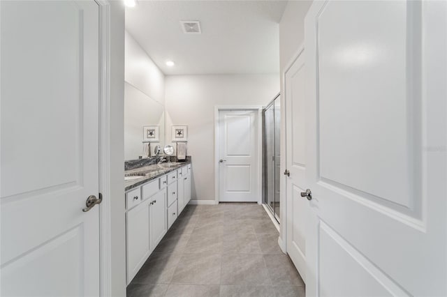 bathroom featuring tile patterned flooring, a shower with shower door, and vanity