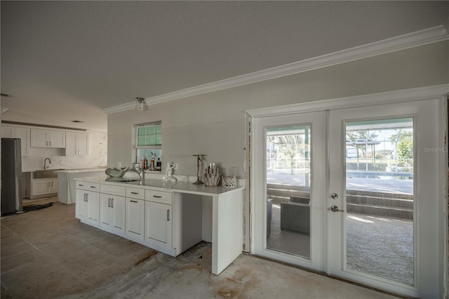 kitchen featuring french doors, stainless steel refrigerator, crown molding, and white cabinets