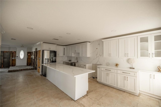 kitchen featuring white cabinetry, sink, crown molding, a center island, and stainless steel fridge