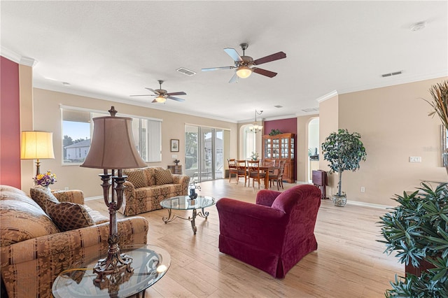 living room featuring ceiling fan, ornamental molding, and light wood-type flooring