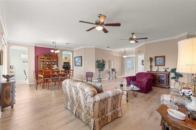 living room featuring crown molding, a ceiling fan, light wood-type flooring, baseboards, and arched walkways