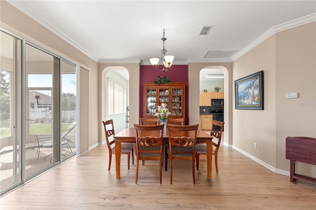 dining room featuring arched walkways, visible vents, and light wood-type flooring