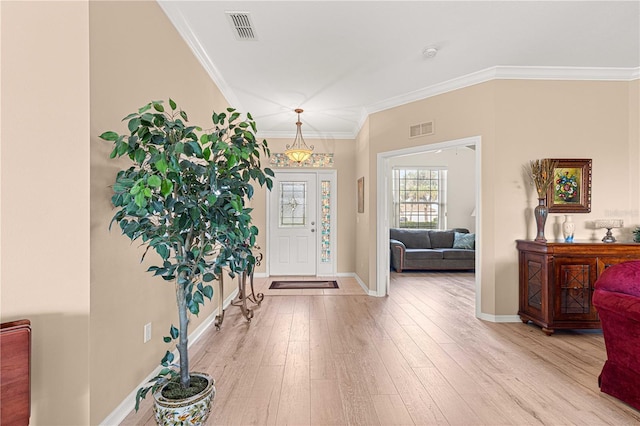foyer entrance featuring wood finished floors, ornamental molding, and visible vents