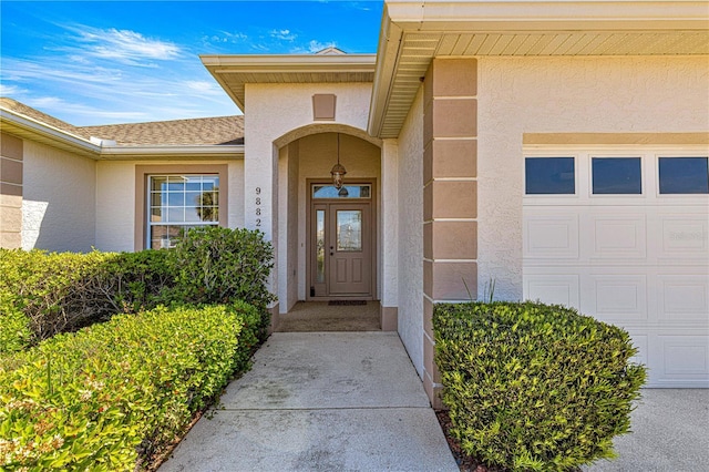 doorway to property featuring stucco siding, roof with shingles, and an attached garage