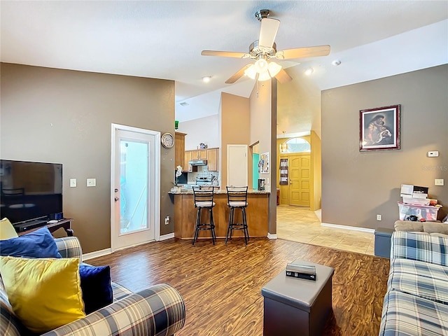 living room with light hardwood / wood-style flooring, ceiling fan, and high vaulted ceiling