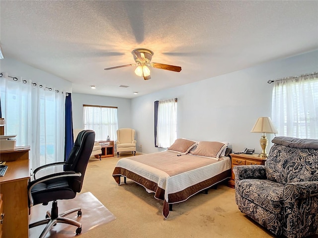 bedroom with light carpet, ceiling fan, and a textured ceiling