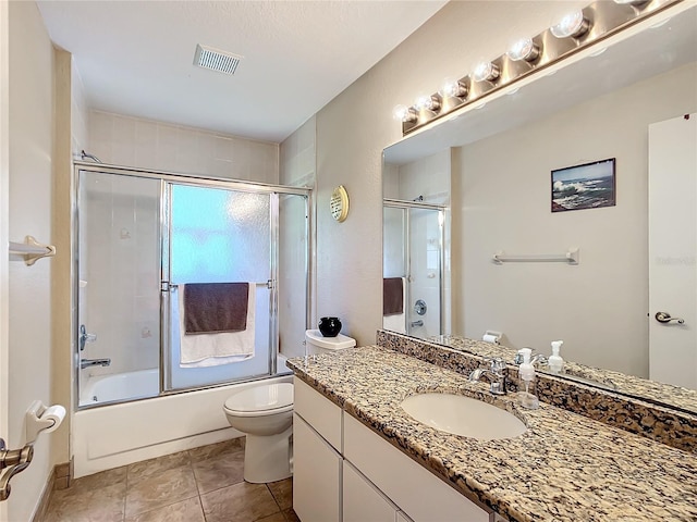 full bathroom featuring tile patterned flooring, bath / shower combo with glass door, toilet, and vanity