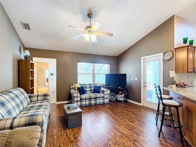 living room with a textured ceiling, lofted ceiling, dark hardwood / wood-style floors, and ceiling fan