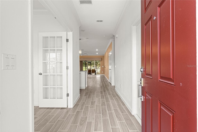 corridor with light hardwood / wood-style flooring and ornamental molding