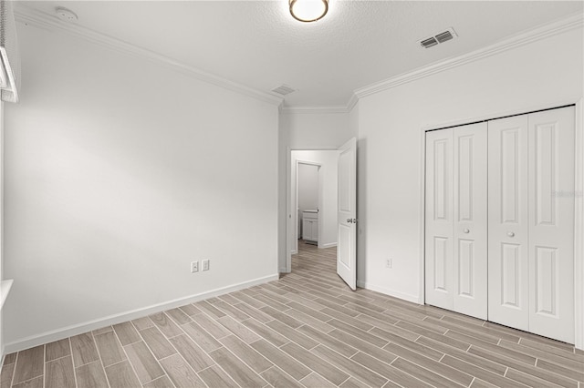 unfurnished bedroom featuring ornamental molding, a textured ceiling, a closet, and light hardwood / wood-style floors