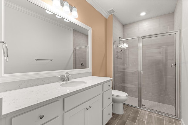 bathroom with ornamental molding, a shower with shower door, vanity, and toilet