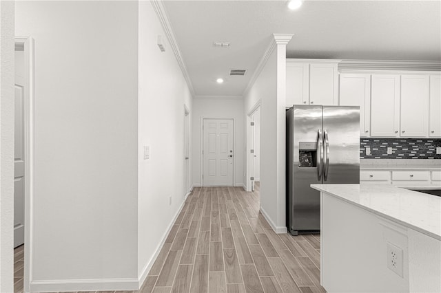 kitchen featuring stainless steel fridge with ice dispenser, white cabinetry, light hardwood / wood-style flooring, and light stone countertops