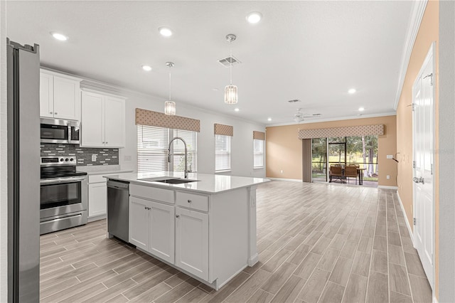 kitchen featuring an island with sink, light wood-type flooring, stainless steel appliances, sink, and white cabinetry