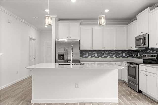 kitchen with hanging light fixtures, a center island with sink, white cabinetry, appliances with stainless steel finishes, and light hardwood / wood-style floors