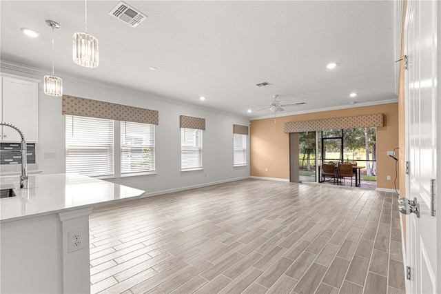 unfurnished living room with ceiling fan, a textured ceiling, crown molding, and light hardwood / wood-style floors