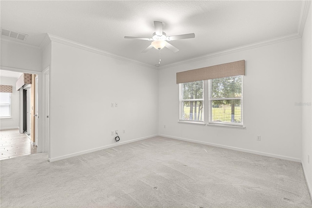 spare room with ornamental molding, light colored carpet, a wealth of natural light, and ceiling fan