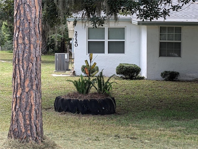 view of side of property featuring a lawn and central air condition unit