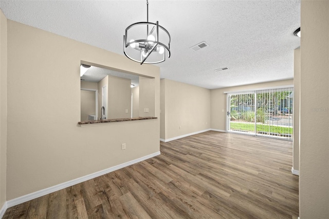 interior space with an inviting chandelier, a textured ceiling, and hardwood / wood-style floors