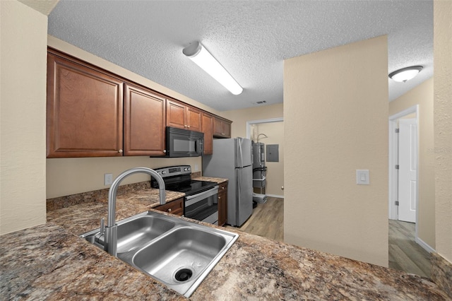 kitchen featuring a textured ceiling, appliances with stainless steel finishes, light wood-type flooring, and sink