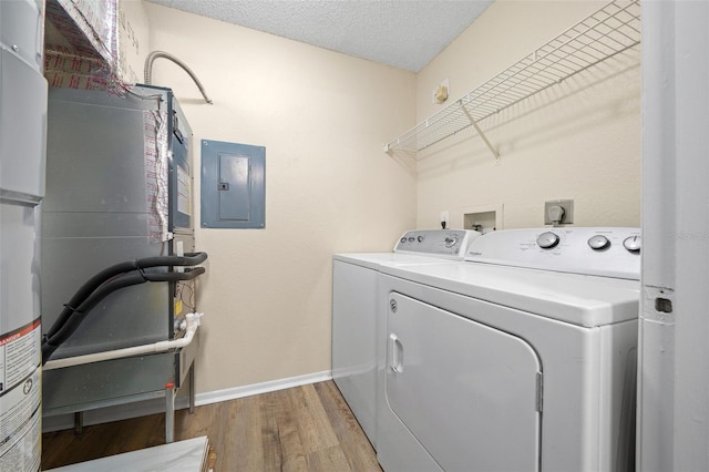 clothes washing area featuring wood-type flooring, electric panel, a textured ceiling, and washing machine and dryer