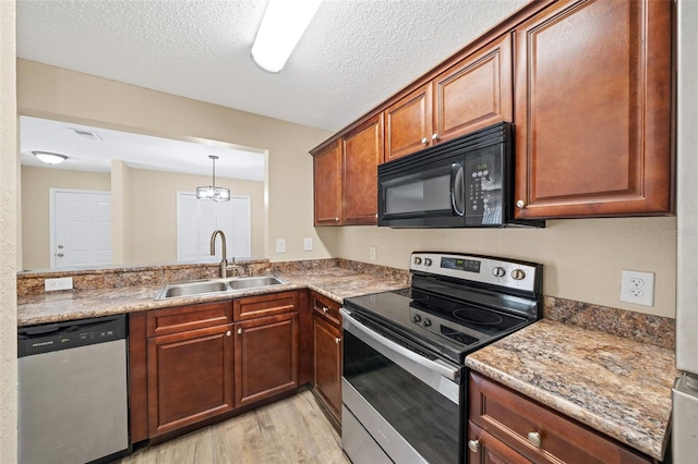 kitchen with sink, stone countertops, a textured ceiling, appliances with stainless steel finishes, and light wood-type flooring