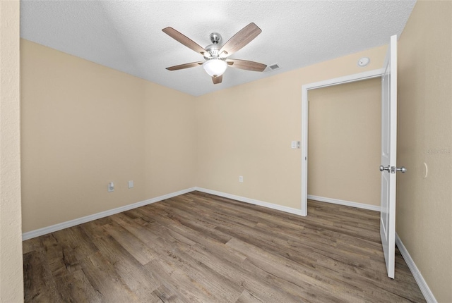 spare room featuring wood-type flooring, ceiling fan, and a textured ceiling