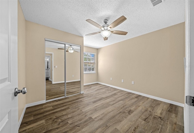 unfurnished bedroom featuring a closet, ceiling fan, hardwood / wood-style floors, and a textured ceiling